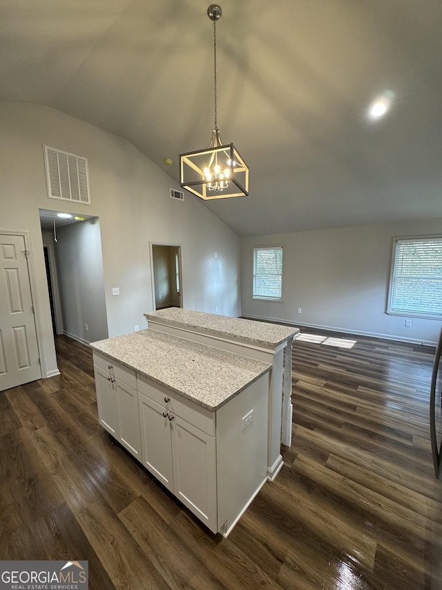 kitchen with light stone counters, decorative light fixtures, dark hardwood / wood-style floors, white cabinetry, and lofted ceiling