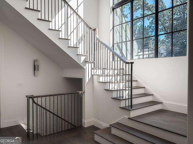 stairway featuring hardwood / wood-style floors, a towering ceiling, and plenty of natural light