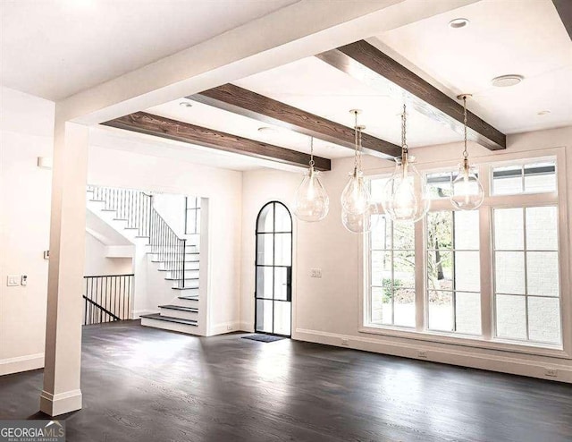 spare room with beamed ceiling, dark wood-type flooring, and a healthy amount of sunlight