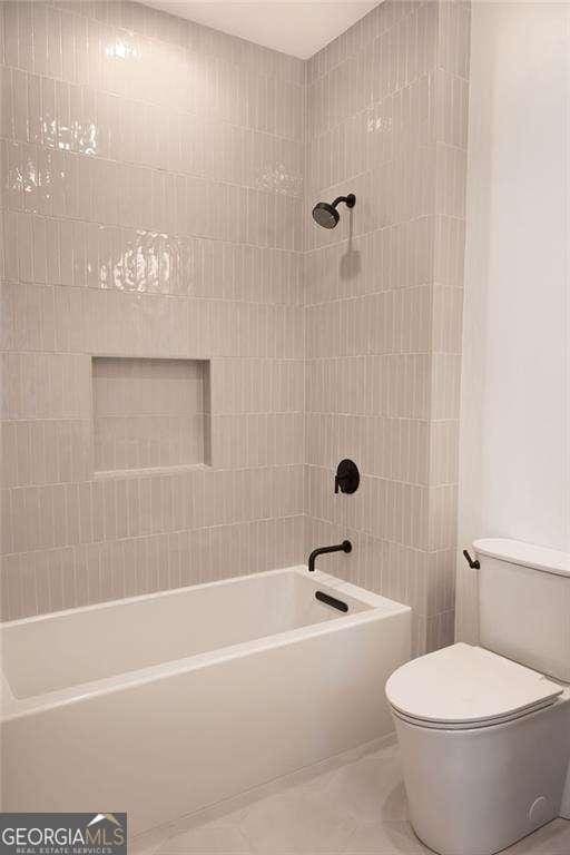 bathroom with tiled shower / bath combo and toilet