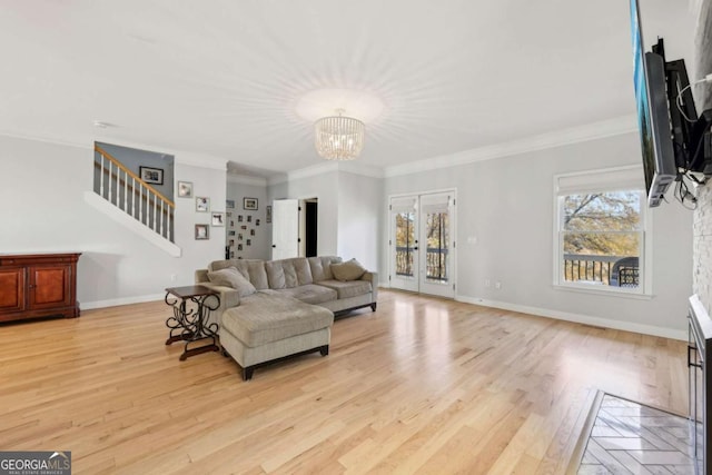 living room with a notable chandelier, light wood-type flooring, and crown molding