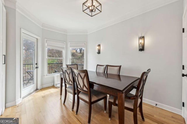 dining space featuring a notable chandelier, light hardwood / wood-style floors, and ornamental molding