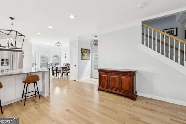 kitchen with a kitchen breakfast bar, light hardwood / wood-style flooring, crown molding, decorative light fixtures, and high end fridge