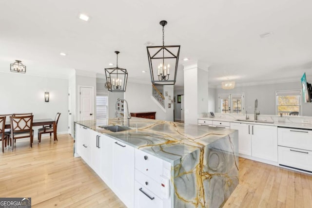 kitchen with a large island, light hardwood / wood-style floors, white cabinetry, and sink