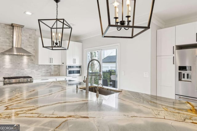 kitchen featuring appliances with stainless steel finishes, light stone counters, sink, wall chimney range hood, and white cabinetry