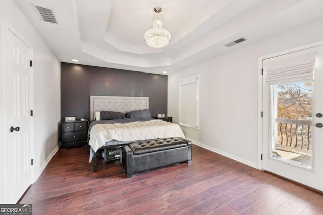 bedroom featuring a raised ceiling, dark hardwood / wood-style flooring, and access to outside