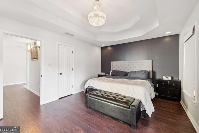 bedroom with a raised ceiling and dark hardwood / wood-style floors