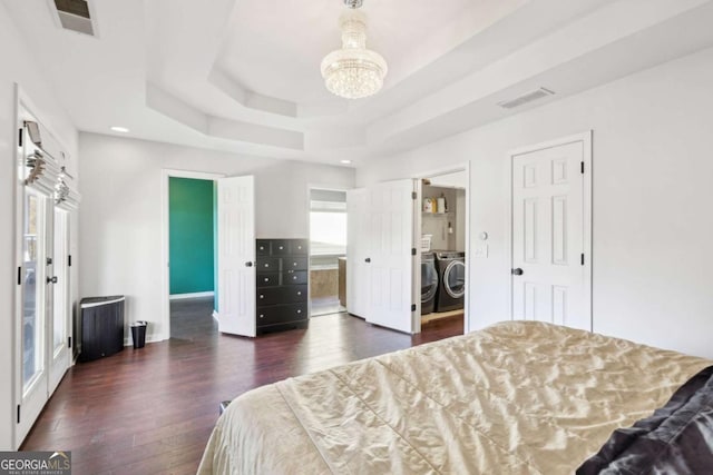 bedroom with connected bathroom, separate washer and dryer, a raised ceiling, and dark hardwood / wood-style floors