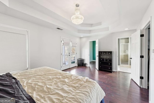 bedroom featuring access to exterior, french doors, dark hardwood / wood-style flooring, ensuite bath, and a tray ceiling