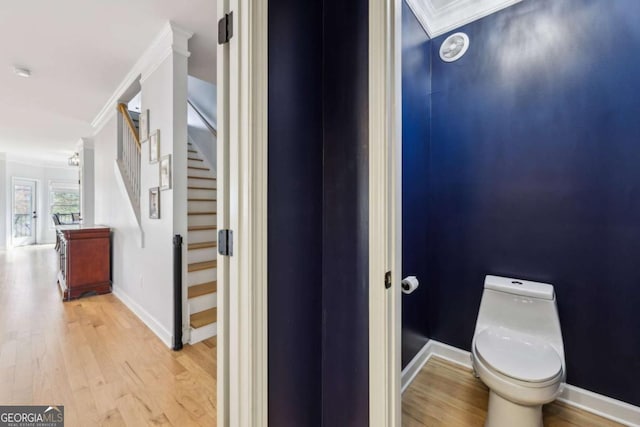 bathroom with hardwood / wood-style flooring, toilet, and crown molding