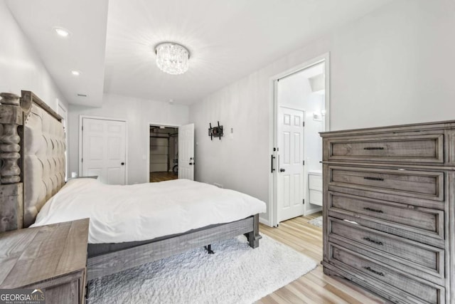 bedroom featuring ensuite bathroom and light wood-type flooring