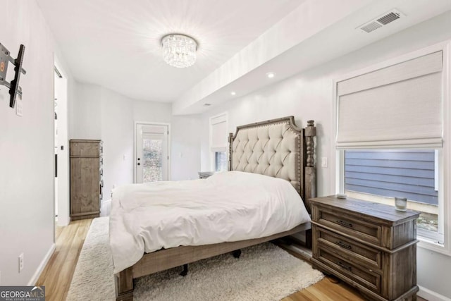 bedroom with light hardwood / wood-style flooring and a notable chandelier