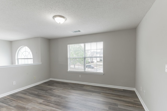 empty room with a textured ceiling and dark wood-type flooring