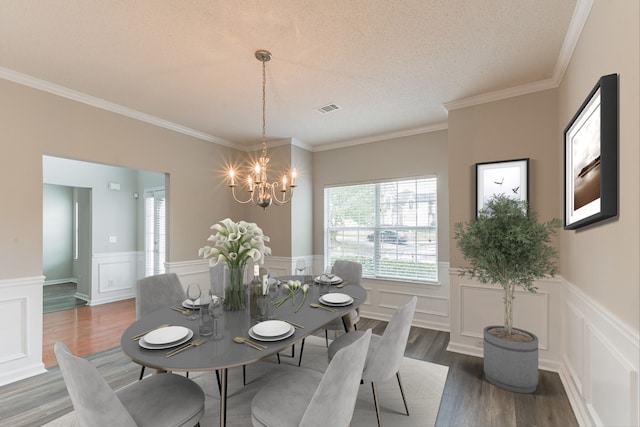 dining area with a textured ceiling, crown molding, dark wood-type flooring, and an inviting chandelier