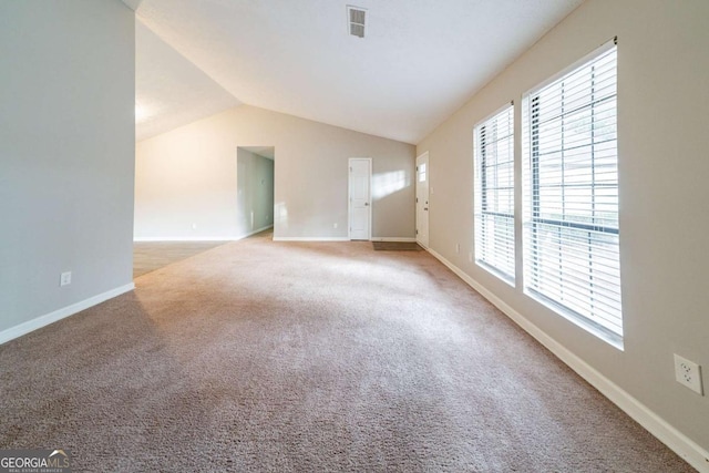 carpeted spare room featuring a healthy amount of sunlight and lofted ceiling