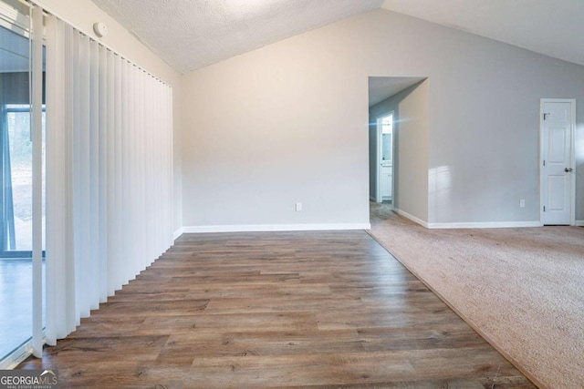 unfurnished room with hardwood / wood-style flooring, a textured ceiling, and vaulted ceiling