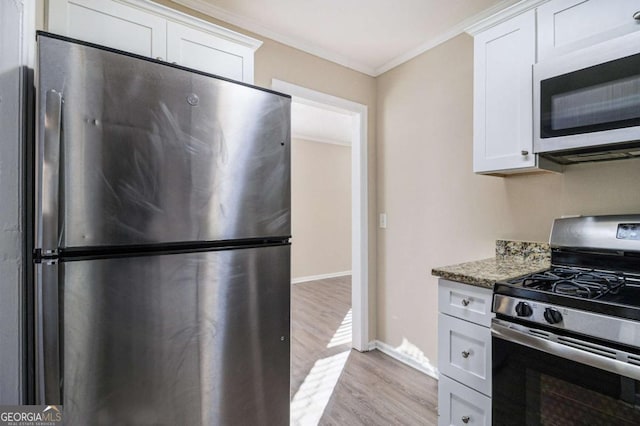 kitchen featuring light wood-type flooring, ornamental molding, stainless steel appliances, stone countertops, and white cabinets