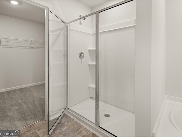 bathroom featuring a shower with door and sink