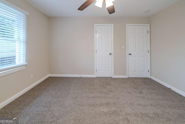 unfurnished bedroom featuring carpet flooring, ceiling fan, and two closets