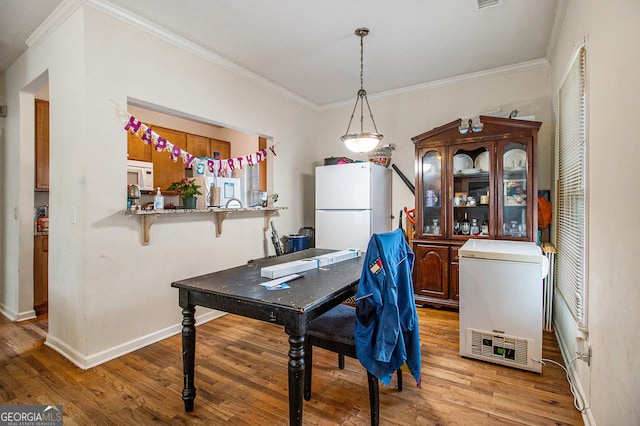 dining space with light hardwood / wood-style floors and crown molding