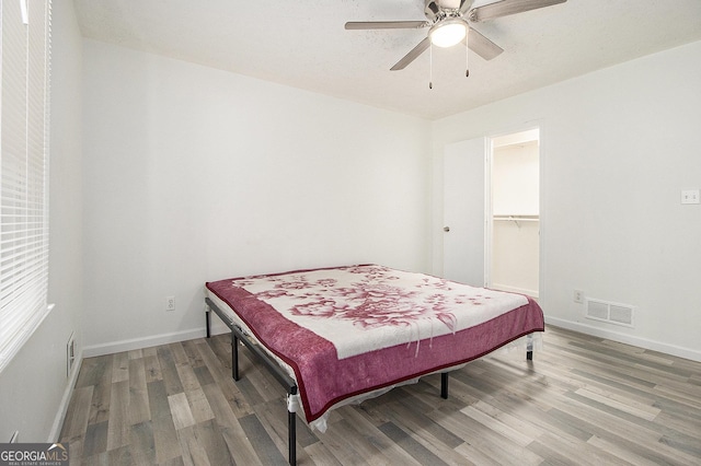 bedroom with ceiling fan, a closet, a spacious closet, and hardwood / wood-style flooring