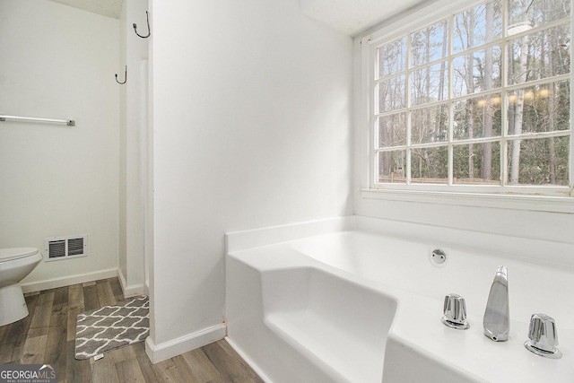 bathroom with toilet, wood-type flooring, and a tub