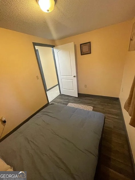 unfurnished bedroom featuring a textured ceiling and dark wood-type flooring