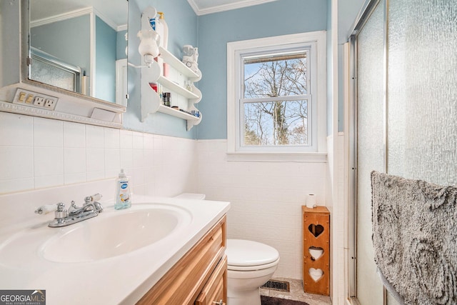 bathroom with an enclosed shower, toilet, vanity, tile walls, and ornamental molding