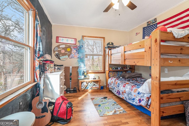 bedroom featuring light wood-type flooring, multiple windows, crown molding, and ceiling fan