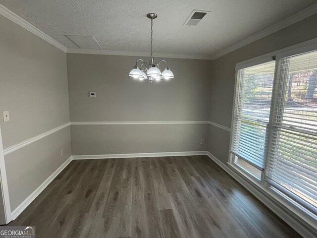 spare room with crown molding, dark hardwood / wood-style flooring, a textured ceiling, and an inviting chandelier