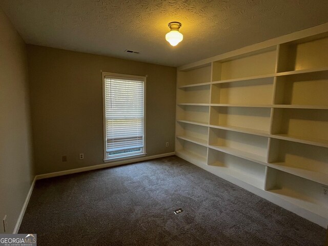 carpeted empty room featuring a textured ceiling