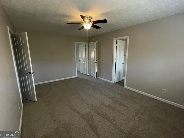 unfurnished bedroom with a textured ceiling, dark carpet, and ceiling fan