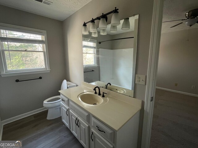 bathroom with ceiling fan, hardwood / wood-style floors, a textured ceiling, toilet, and vanity