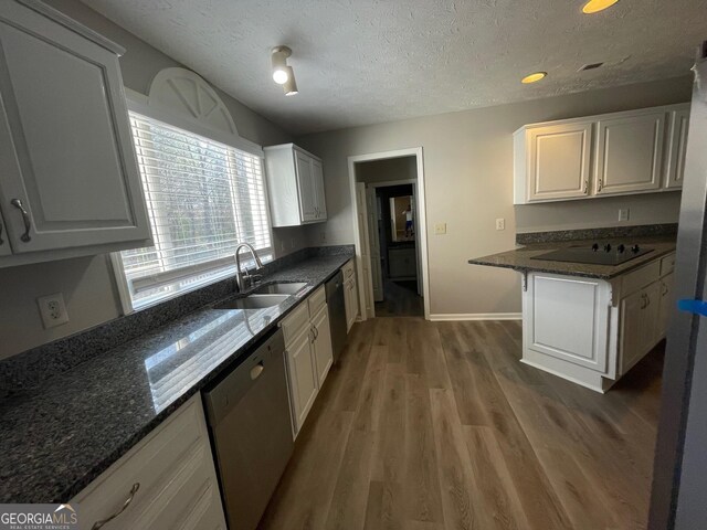 kitchen featuring a textured ceiling, sink, dishwasher, hardwood / wood-style floors, and white cabinetry