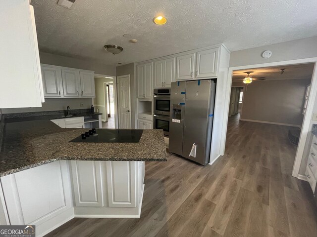 kitchen featuring kitchen peninsula, white cabinetry, dark wood-type flooring, and appliances with stainless steel finishes