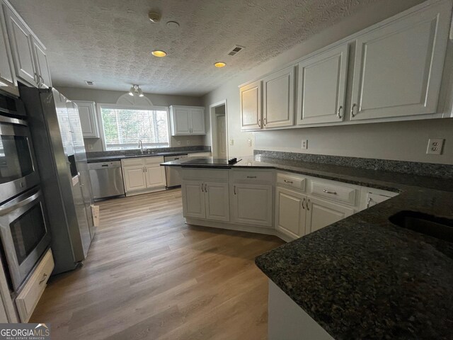 kitchen with light wood-type flooring, white cabinetry, and stainless steel appliances