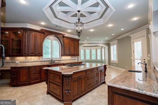 kitchen featuring a center island with sink, ornamental molding, sink, and hanging light fixtures