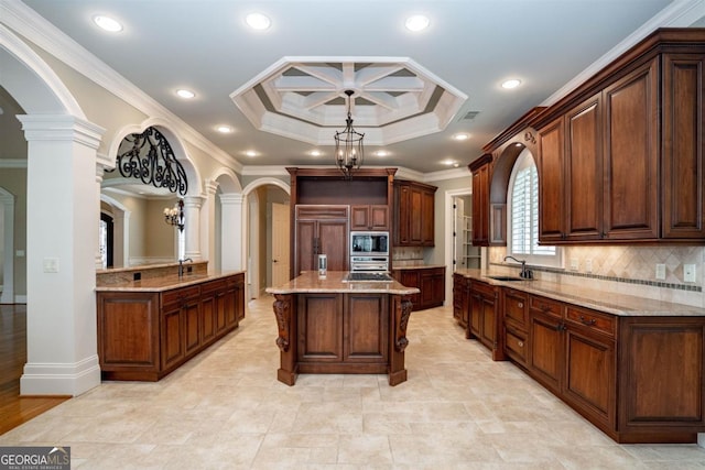 kitchen featuring ornate columns, sink, a kitchen island, and ornamental molding