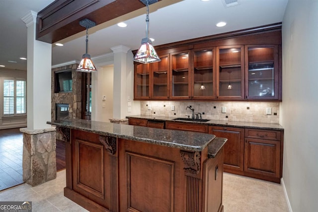 bar with sink, ornamental molding, a fireplace, decorative light fixtures, and light hardwood / wood-style floors