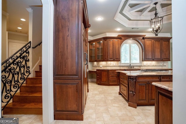 kitchen with pendant lighting, backsplash, crown molding, light stone countertops, and a notable chandelier