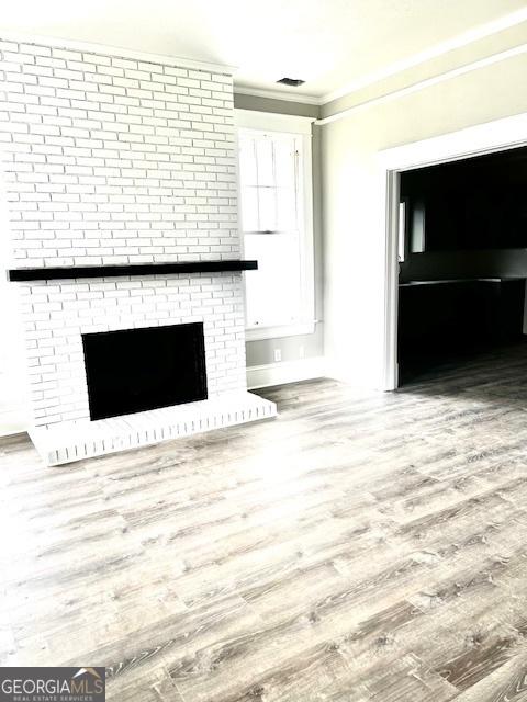 interior space with a fireplace, ornamental molding, and hardwood / wood-style flooring