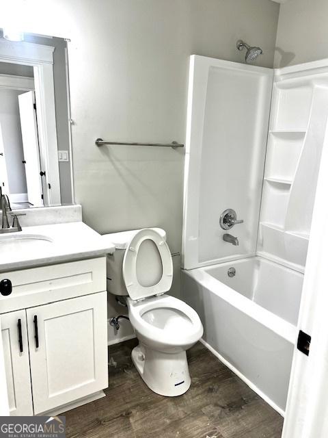 full bathroom featuring hardwood / wood-style flooring, vanity, toilet, and bathtub / shower combination