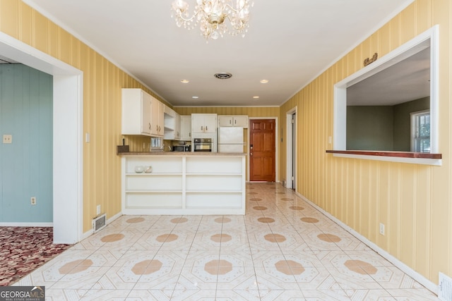 kitchen featuring kitchen peninsula, white refrigerator, crown molding, and stainless steel oven