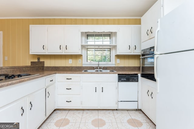 kitchen with sink, white appliances, wooden walls, white cabinets, and ornamental molding