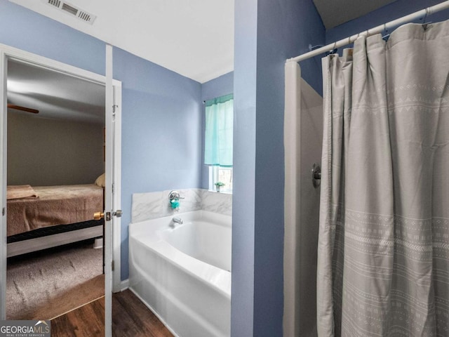 bathroom featuring hardwood / wood-style flooring, a tub to relax in, and vaulted ceiling