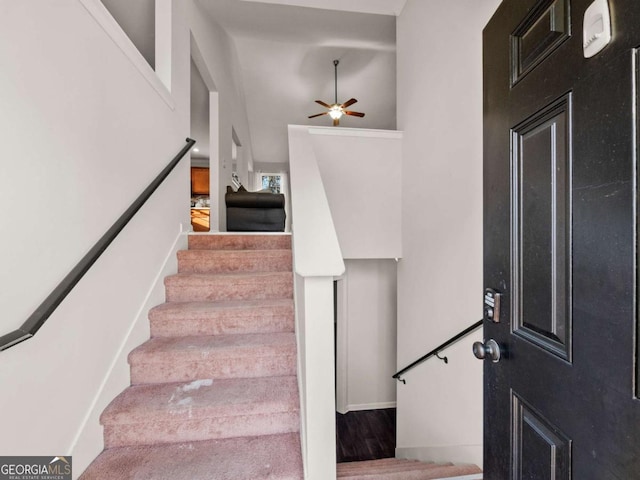 stairway with ceiling fan and wood-type flooring