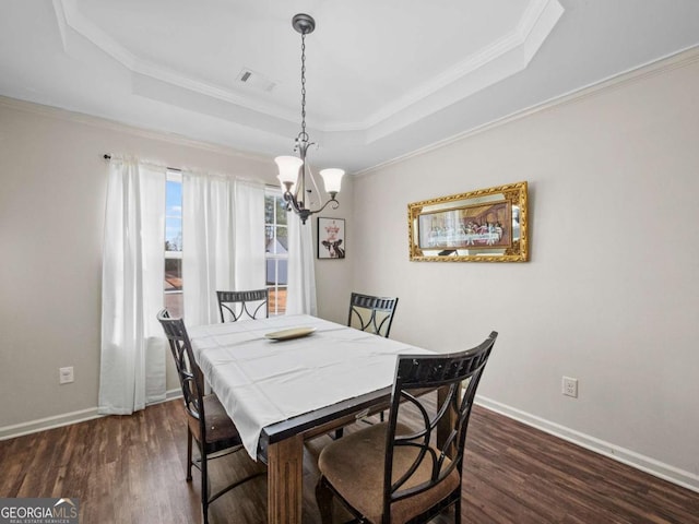 dining room with dark hardwood / wood-style floors, a raised ceiling, and ornamental molding