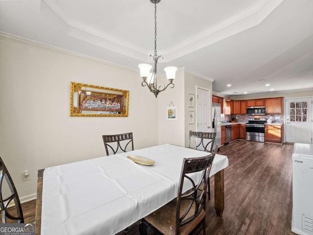 dining space with a raised ceiling, dark hardwood / wood-style flooring, an inviting chandelier, and ornamental molding