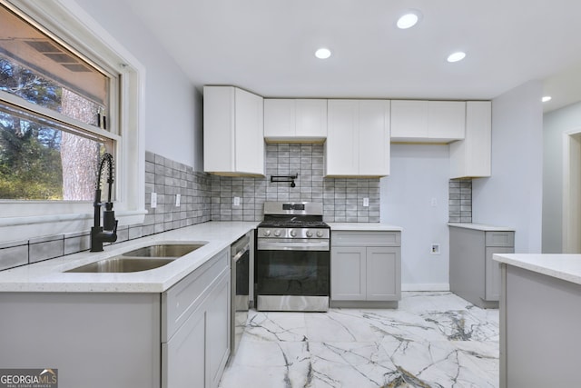 kitchen with gray cabinetry, sink, light stone countertops, appliances with stainless steel finishes, and tasteful backsplash