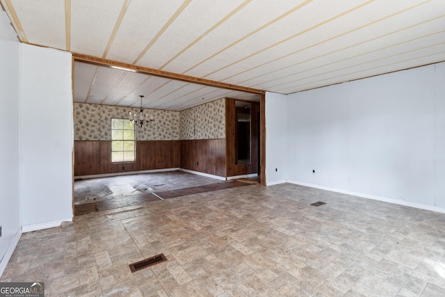 empty room with a notable chandelier and wood walls